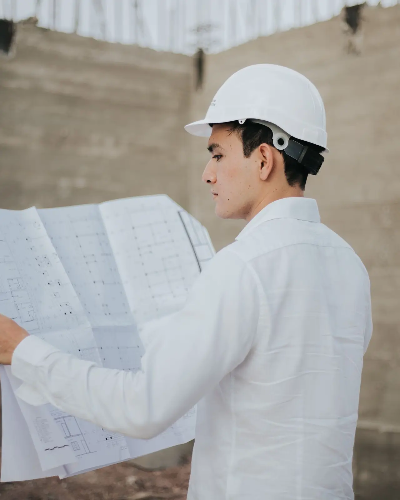 Ingeniero con casco revisando planos en obra