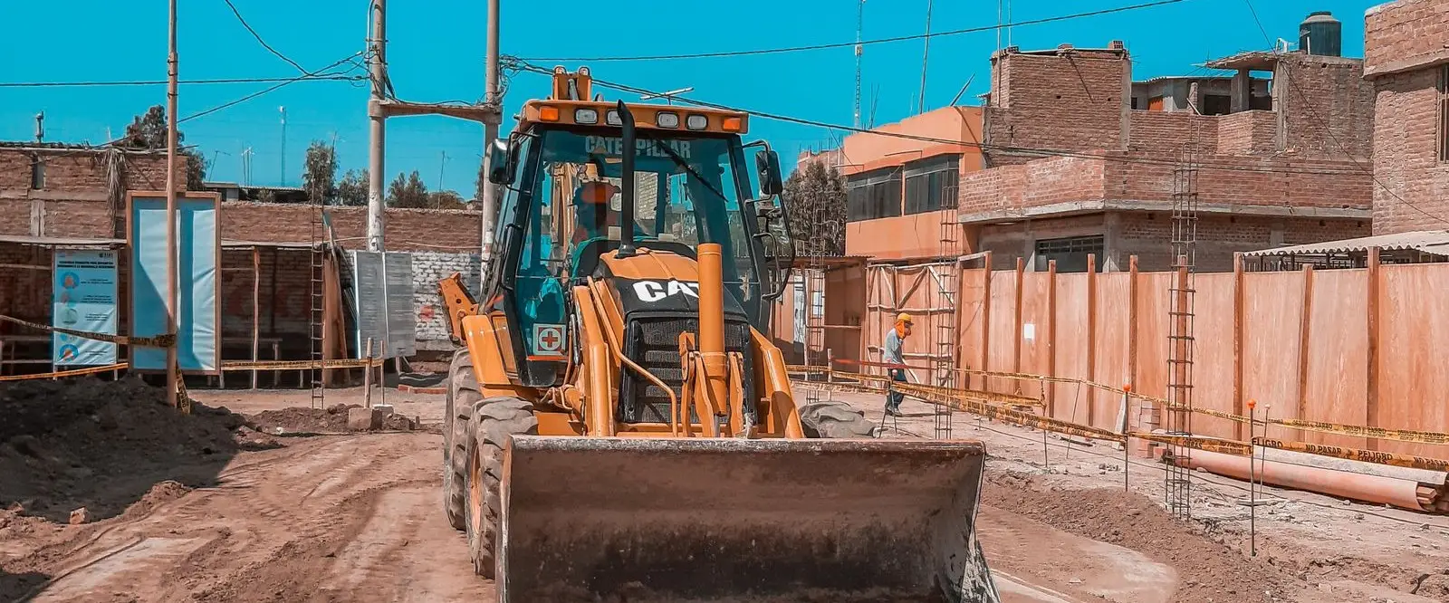 Retroexcavadora conformando la subrasante de una vía urbana